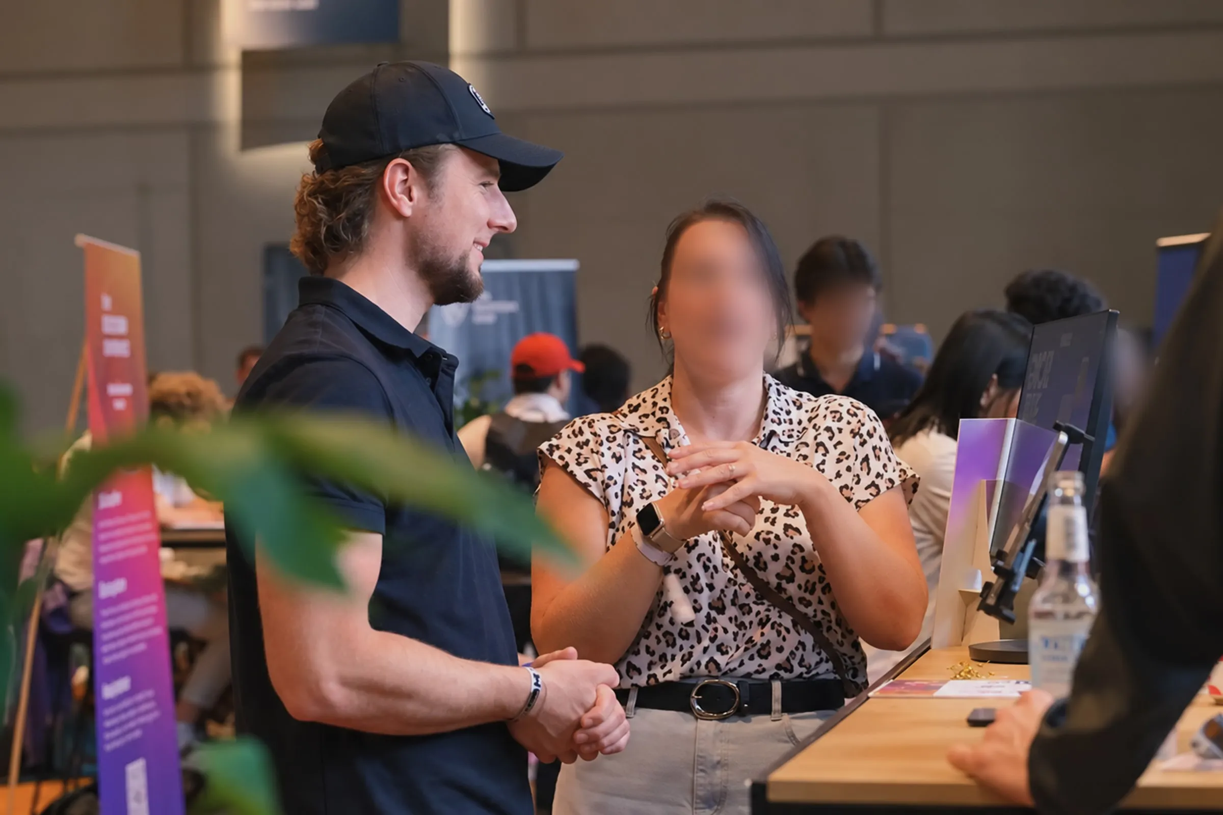 Two people talking at a booth at DappCon