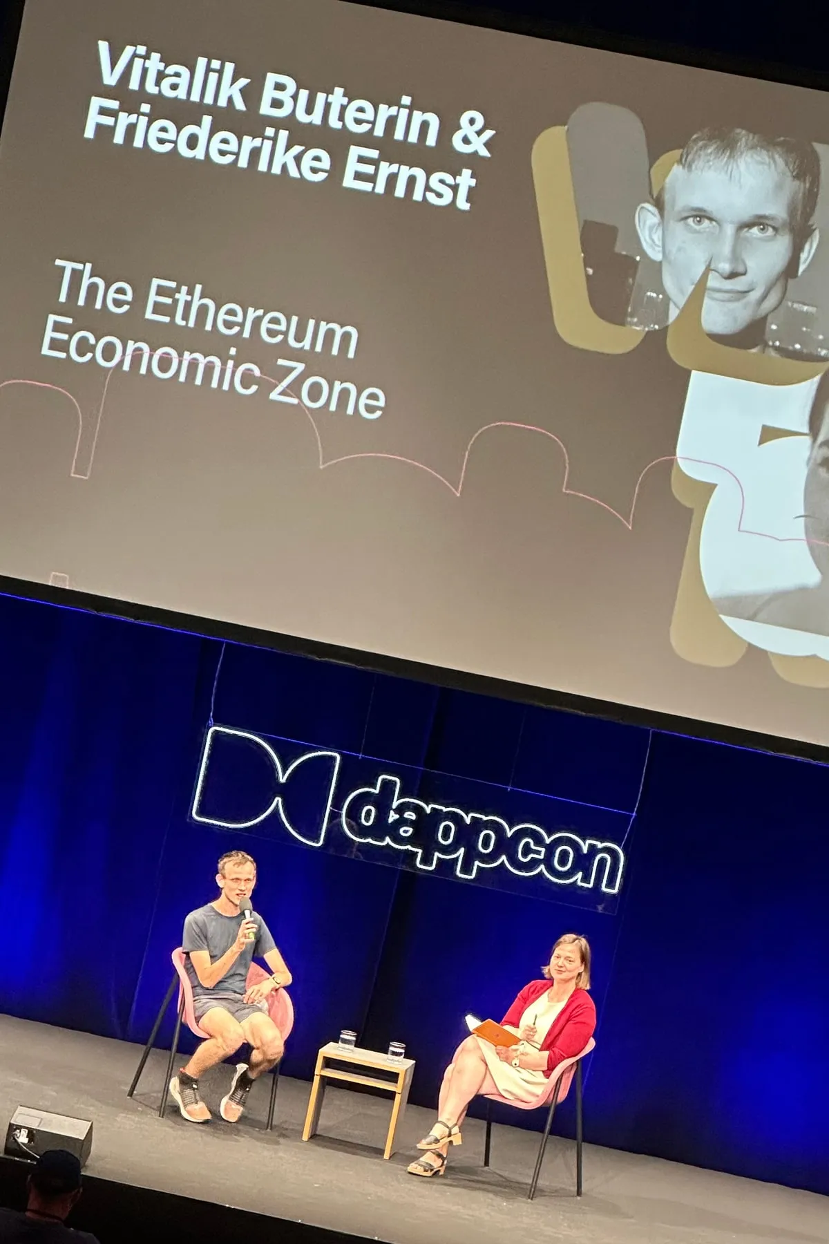 Vitalik Buterin and Friederike Ernst on the DappCon main stage, under a screen reading The Ethereum Economic Zone
